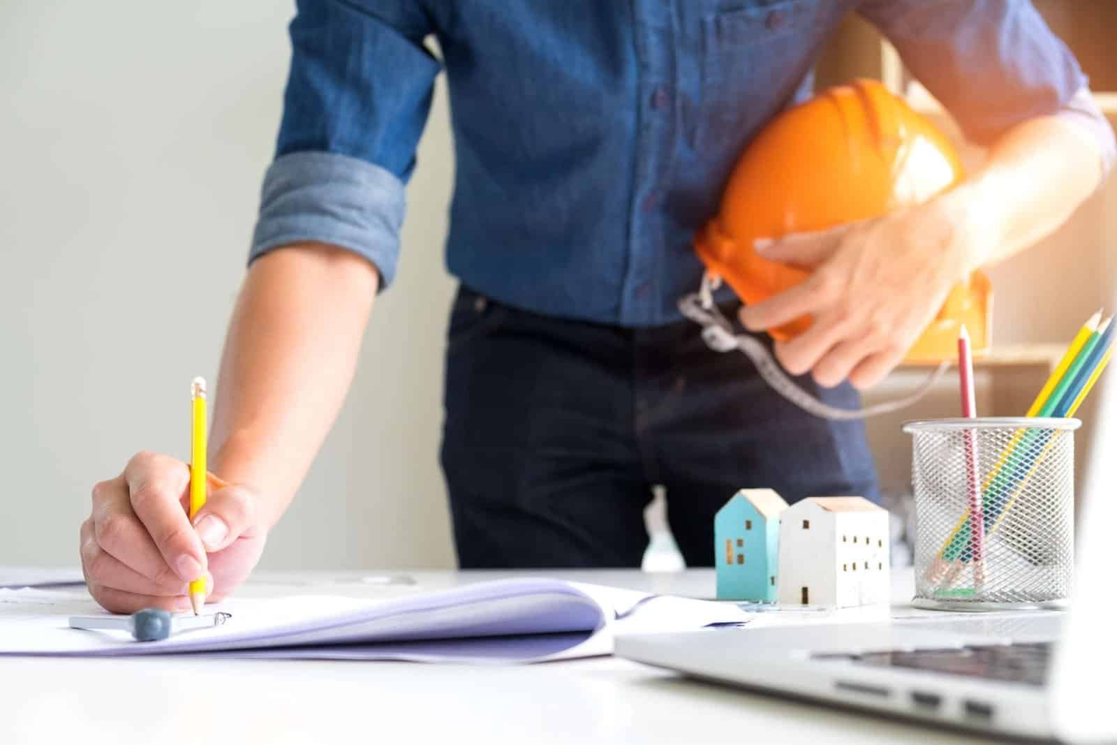 High-quality construction planning with a builder holding an orange safety helmet at a desk.