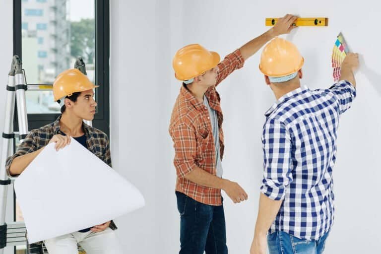 Construction workers measuring and planning a building project indoors.