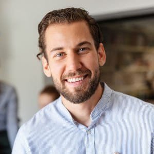 A smiling man in a professional setting, representing construction or project management.